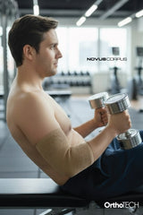 Spor salonunda Novus Corpus OrthoTech bej örgü dirseklik kullanan erkek